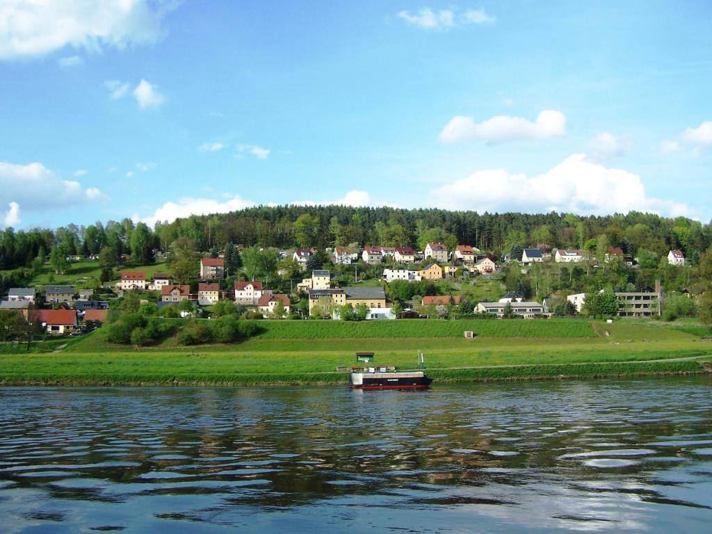 a boat on the water in front of a town at Ferienwohnung Büchsenhof in Prossen