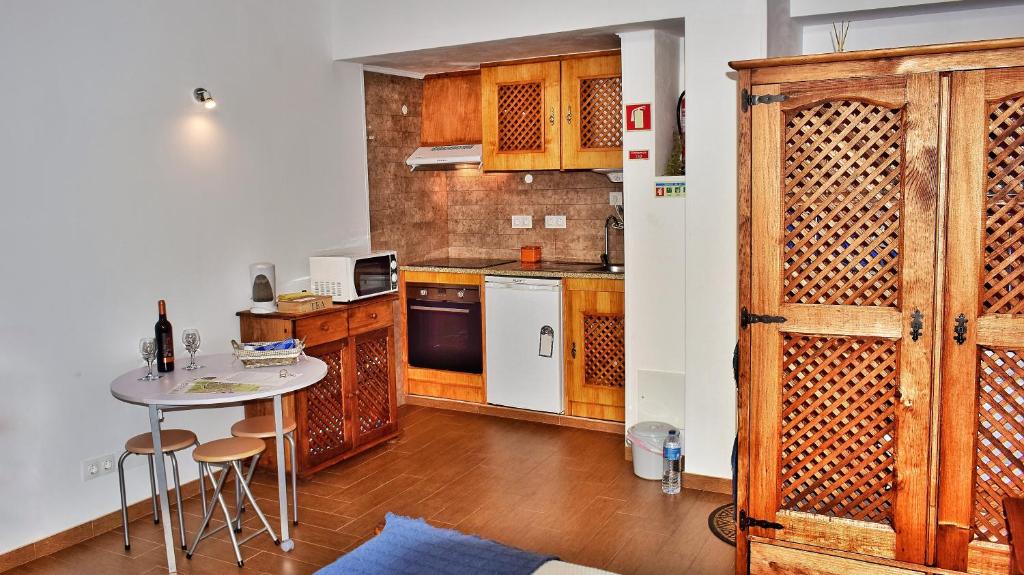 una cocina con armarios de madera y una mesa con taburetes en Bella's House en Évora