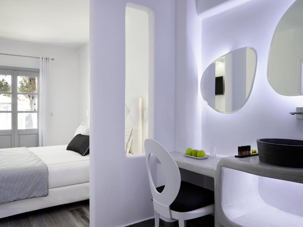 a white room with a bed and a sink and a mirror at Kalisti Hotel & Suites in Fira