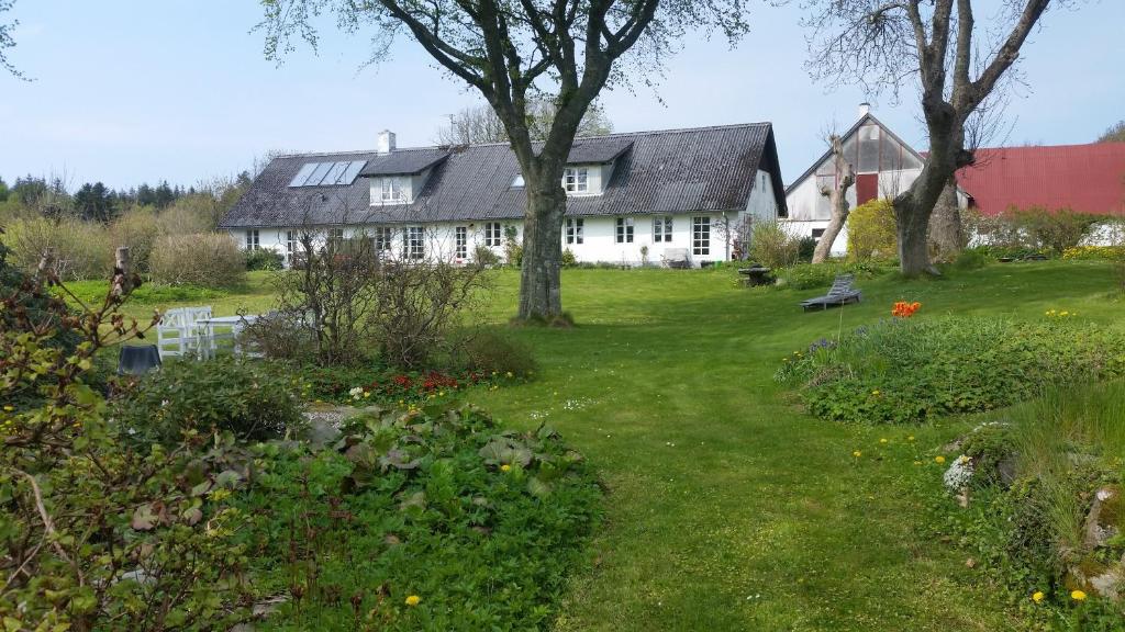 una grande casa bianca con un albero e un cortile di Slettegaard a Slettestrand
