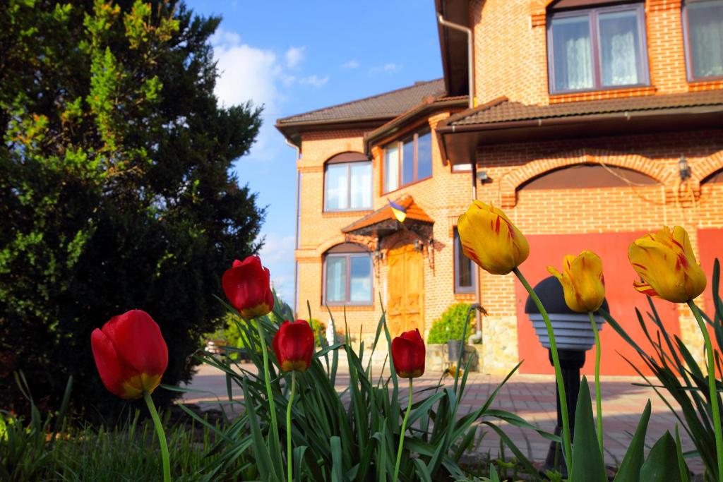 a group of red and yellow flowers in front of a building at Villa Ignatyeva in Skhidnitsa