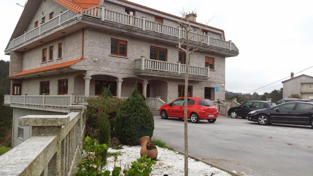 un coche rojo estacionado frente a un edificio en Alojamientos A Pedra, en Dumbría