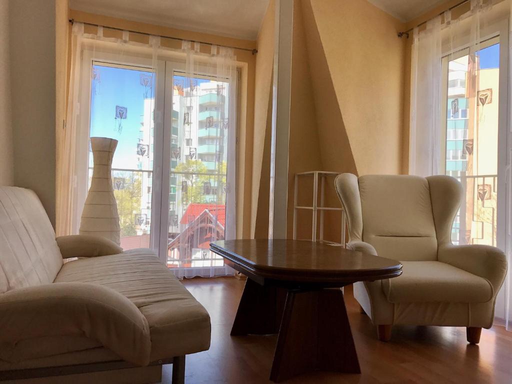 sala de estar con 2 sillas, mesa y ventana en Apartament Onyx en Międzyzdroje