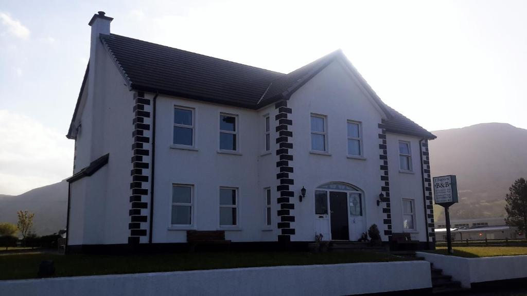 a white house with a black roof at 1 Bayview in Glenariff