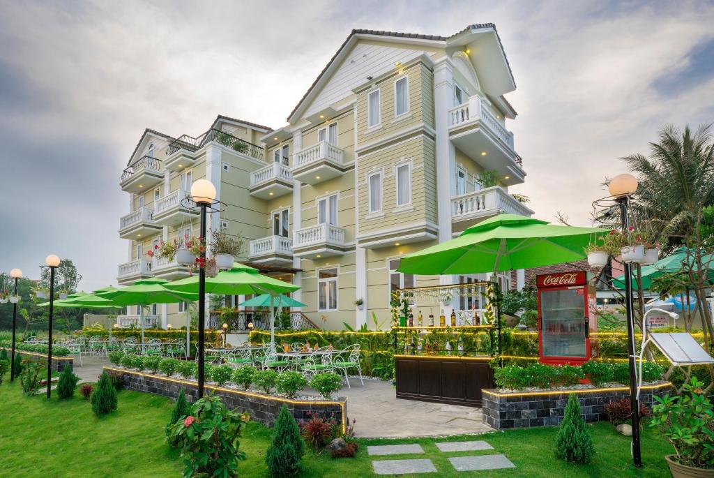 un gran edificio con sombrillas verdes delante en Golden Bell Backpacker Hotel & Pool Bar, en Hoi An