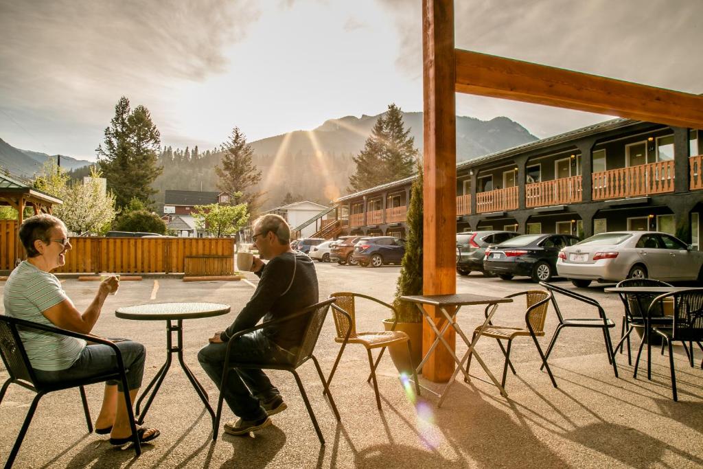 un hombre y una mujer sentados en una mesa en un patio en Crystal Springs Lodge, en Radium Hot Springs