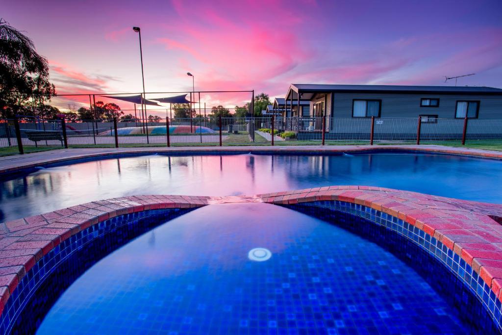 a large swimming pool with a sunset in the background at NRMA Yarrawonga Mulwala Holiday Park in Mulwala