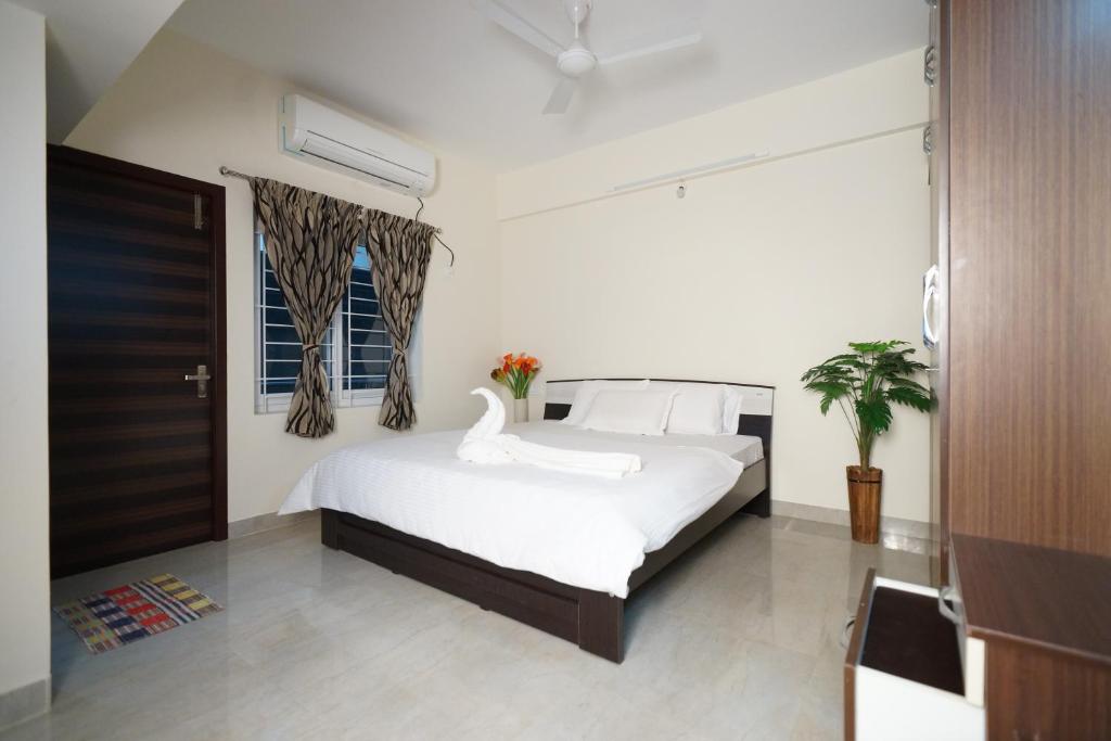 a bedroom with a white bed with a swan on it at Krishna Vibe Service Apartment in Tiruchirappalli