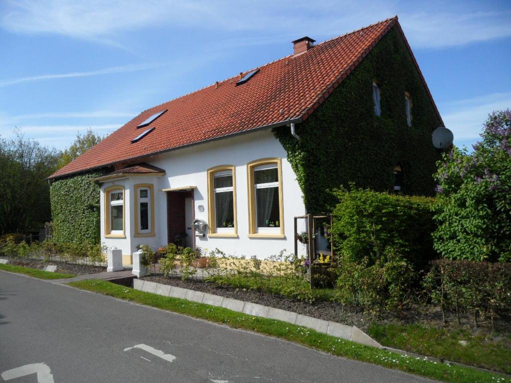 una pequeña casa blanca con techo rojo en Frieslands Ferienwohnung en Bockhorn