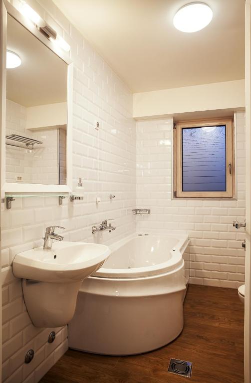 a white bathroom with a sink and a tub and a mirror at Castello Boutique Hotel in Čačak