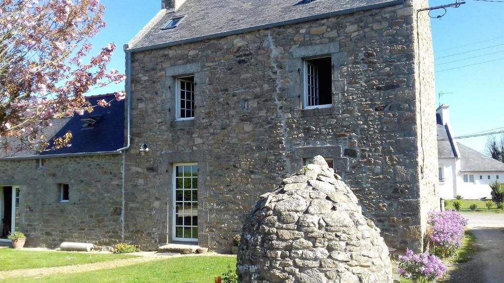 an old stone building with a statue in front of it at Oudoty in Kerlouan