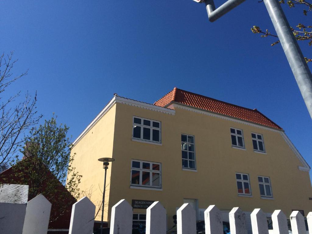 ein gelbes Gebäude mit einem weißen Zaun davor in der Unterkunft Villa Holger in Skagen