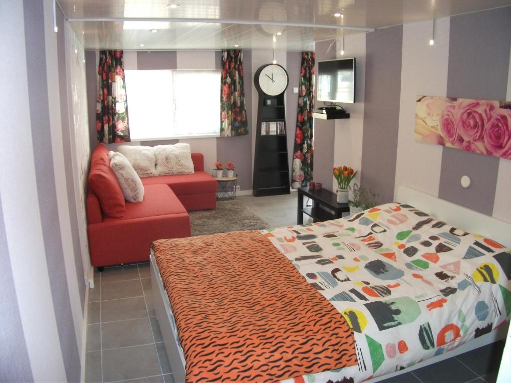 een slaapkamer met een bed en een bank bij Studio Callanya in Callantsoog