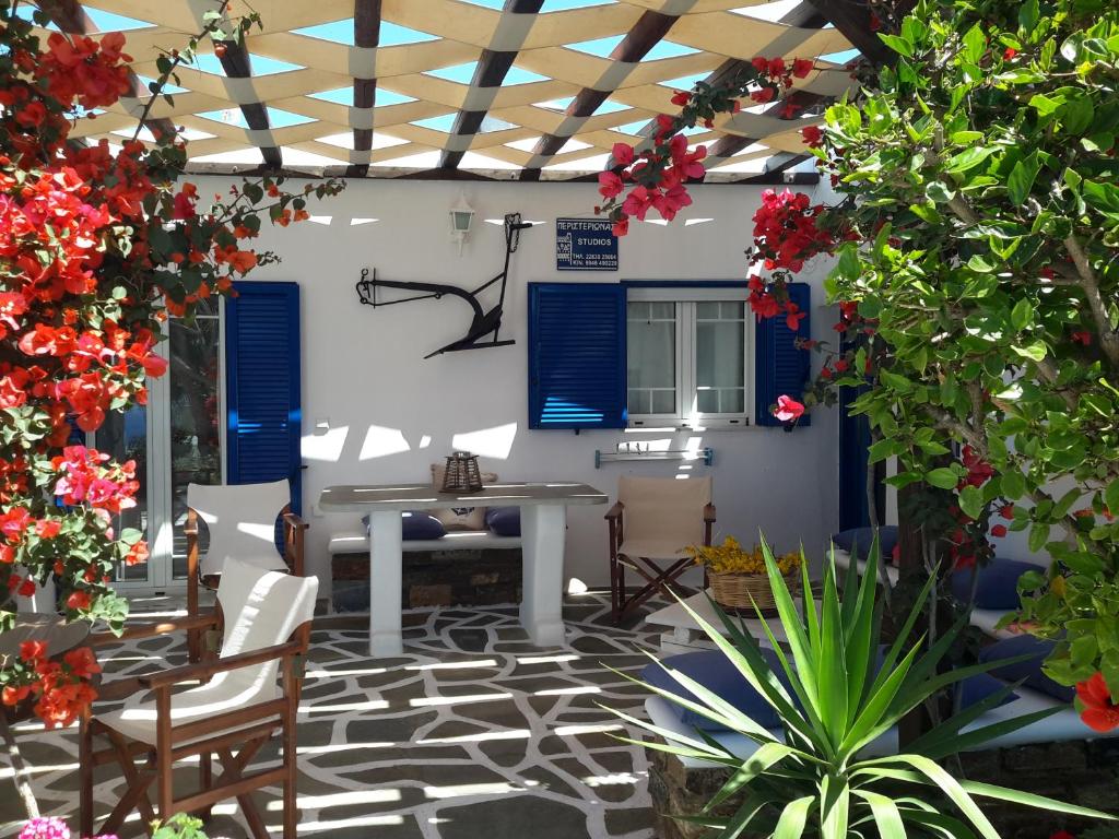 a patio with a table and chairs and flowers at Tinos Peristerionas in Tinos