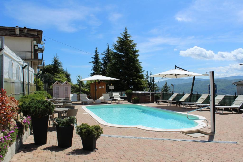 a swimming pool with chairs and umbrellas on a building at Albergo Ristorante Miramonti Toano in Toano