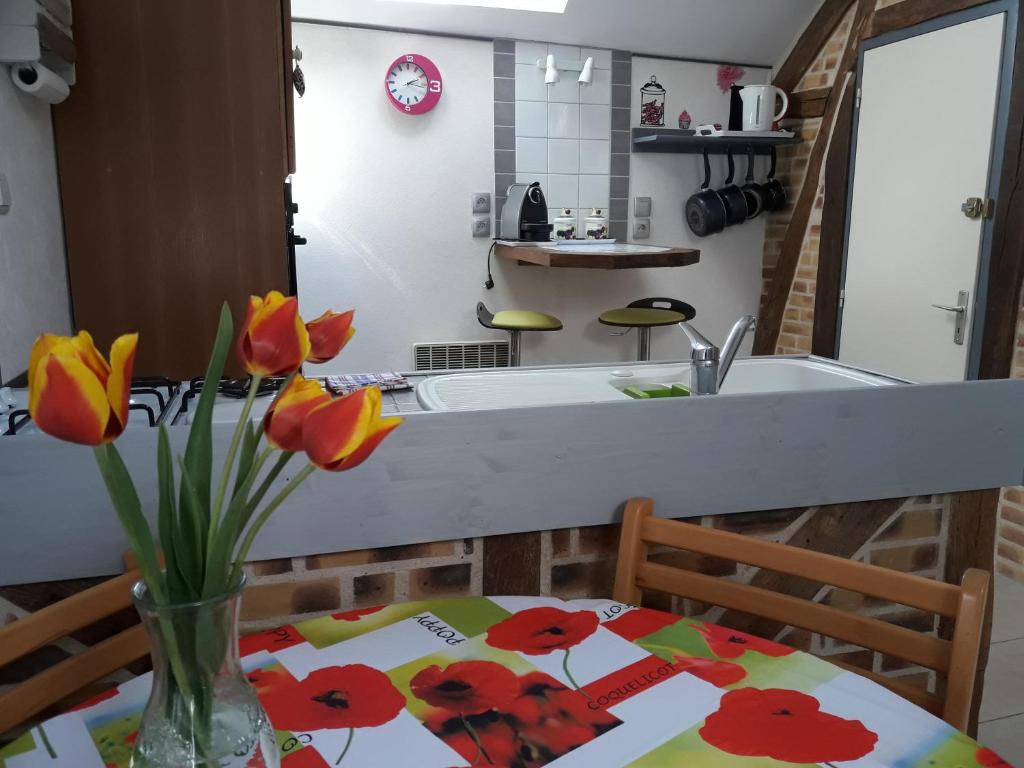 eine Küche mit einem Tisch und einer Blumenvase darauf in der Unterkunft Fée maison with love appartement in Cuissai