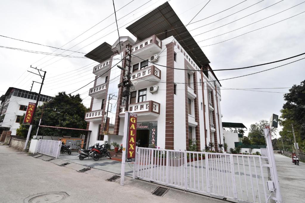 德拉敦Hotel Galaxy的前面有栅栏的白色建筑