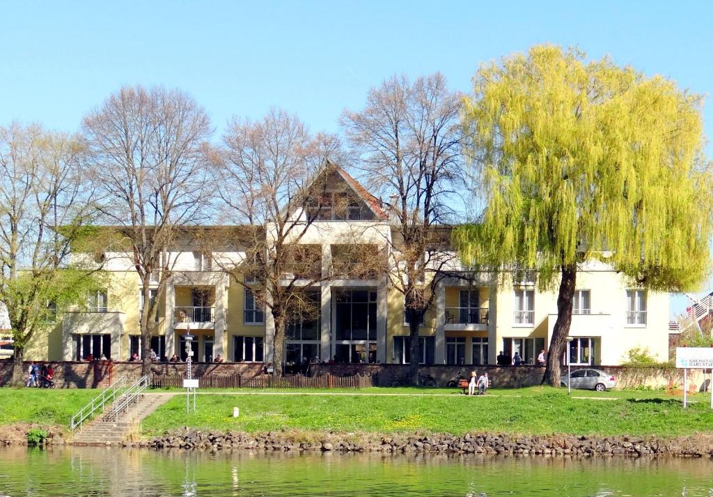 a large white house on the banks of a river at Hotel Mainpromenade ***S in Karlstadt