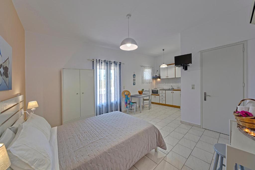 a white bedroom with a bed and a kitchen at Letta's Apartments in Finikas