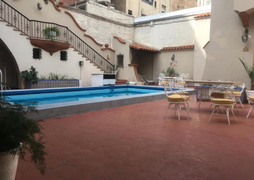 a pool in the courtyard of a building with chairs and a table at Peatonal Colonial in Mendoza