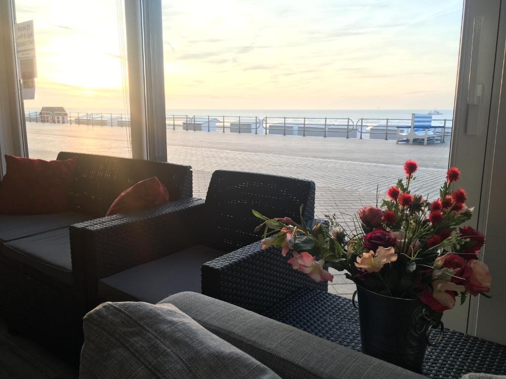 a living room with a couch and a vase with flowers at Zeedijk Westende 8p App in Westende-Bad
