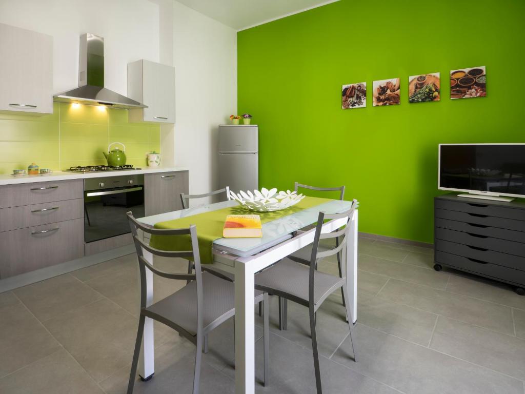 マリーナ・ディ・ラグーザにあるsiciliacasevacanze - Irideの緑の壁、テーブルと椅子付きのキッチンが備わります。