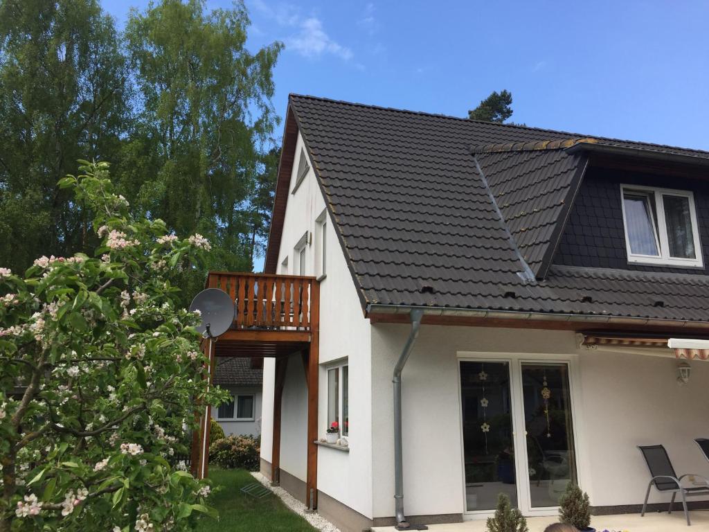 a white house with a black roof at Ferienwohnung "Am Walde" in Lubmin