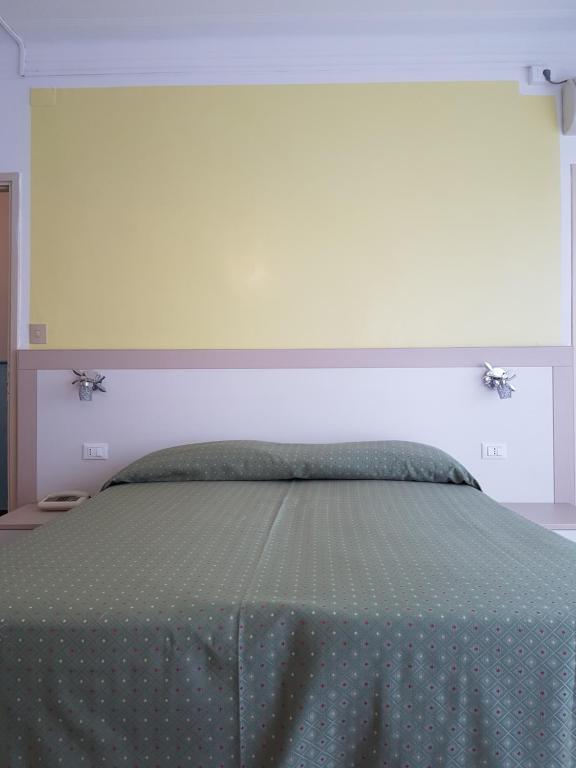 a bedroom with a bed with a green comforter at Hotel Mignon in Alassio