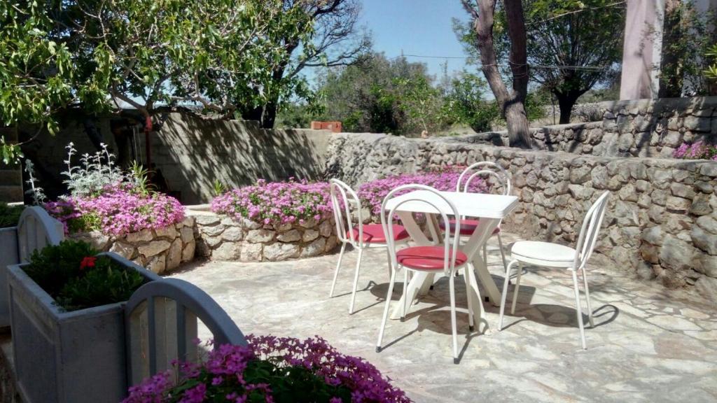 a patio with a table and chairs and a stone wall at Jakišnica Apartment in Lun