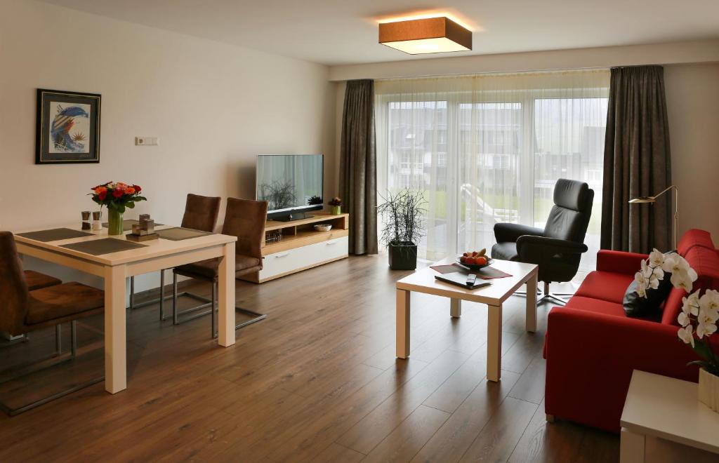 a living room with a red couch and a table at Ferienwohnung zur Schönen Aussicht-Rüters Parkhotel in Willingen