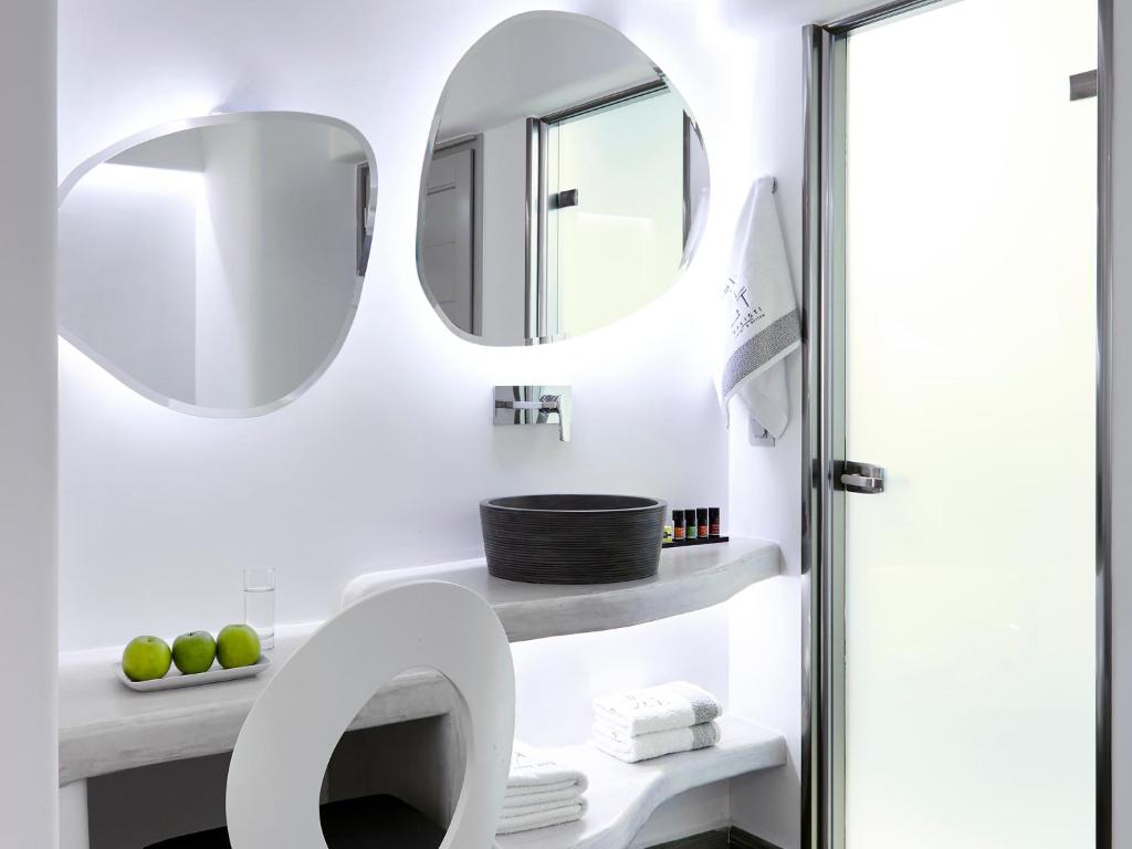 a bathroom with two mirrors and a sink at Kalisti Hotel & Suites in Fira