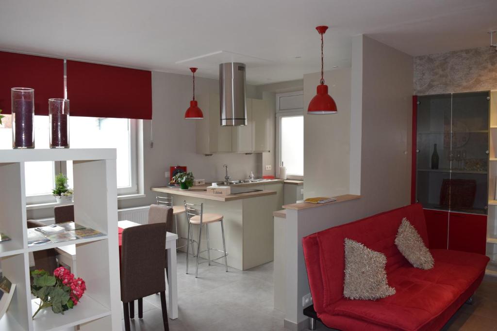 een woonkamer met een rode bank en een keuken bij Au Temps de Spa Le 7 Heures in Spa