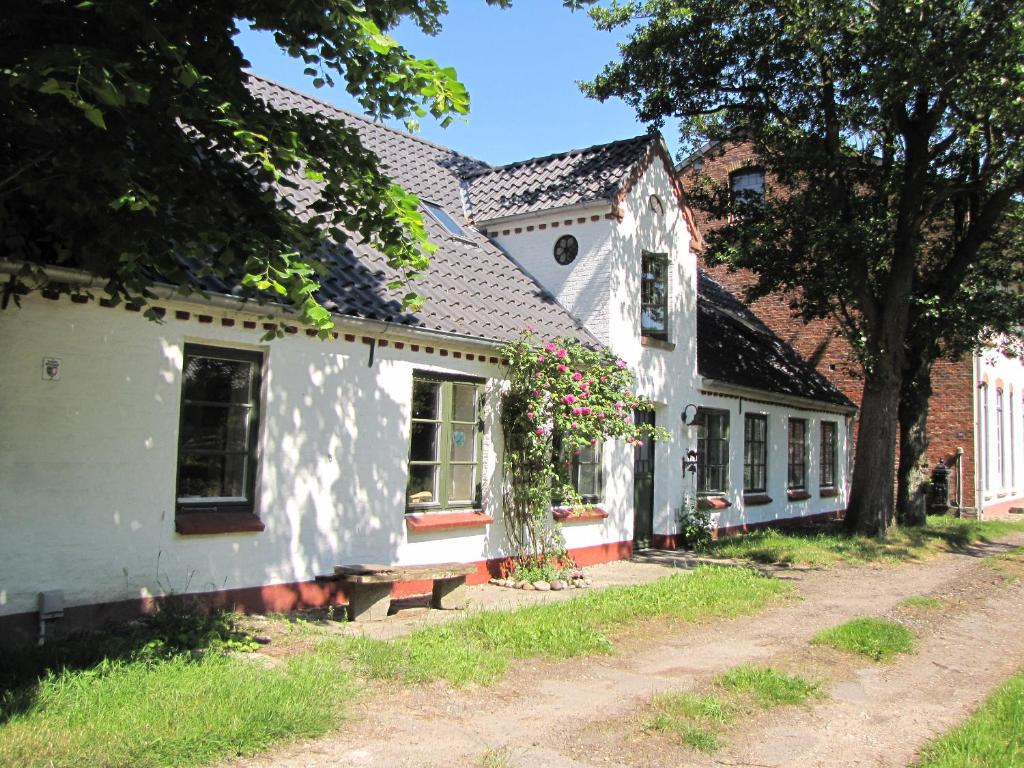 Una casa blanca con flores a un lado. en Ferienwohnung Suederbootfahrt, en Katingsiel