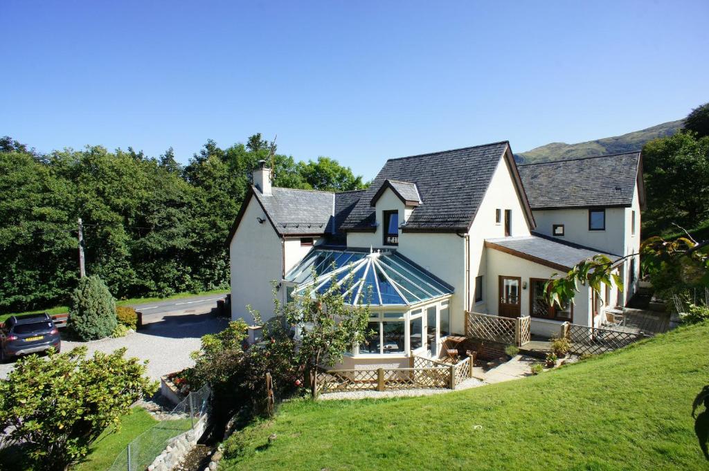 une maison blanche avec une véranda sur le côté dans l'établissement Ben Nevis Guest House, à Fort William