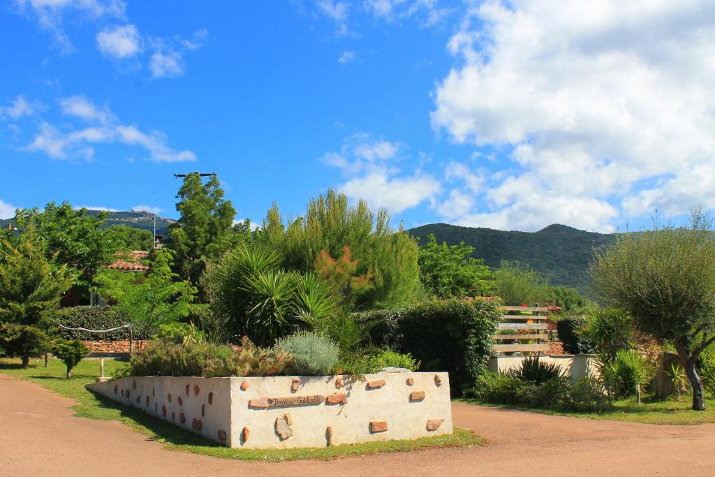 a stone wall in a garden with trees and mountains at Caseddu Di Poggiale in Figari