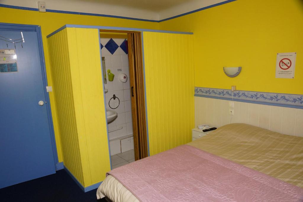 a yellow room with a bed and a bathroom at Le Richelieu in Le Boulou