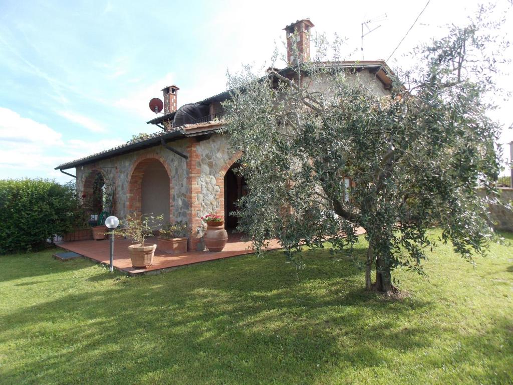 a small stone house with a tree in a yard at Casale Le Querciole in Castiglione dʼOrcia