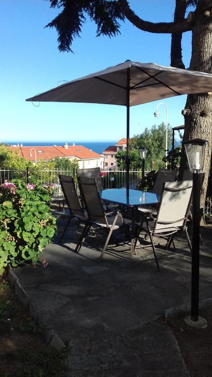 Appartamento con giardino privato في سانتو ستيفانو أل ماري: طاولة وكراسي تحت مظلة على الفناء