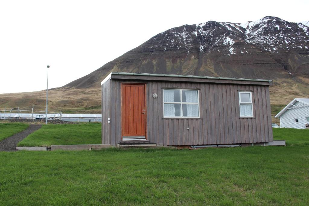 uma pequena casa com uma porta vermelha em frente a uma montanha em Fornhagi 2 em Akureyri