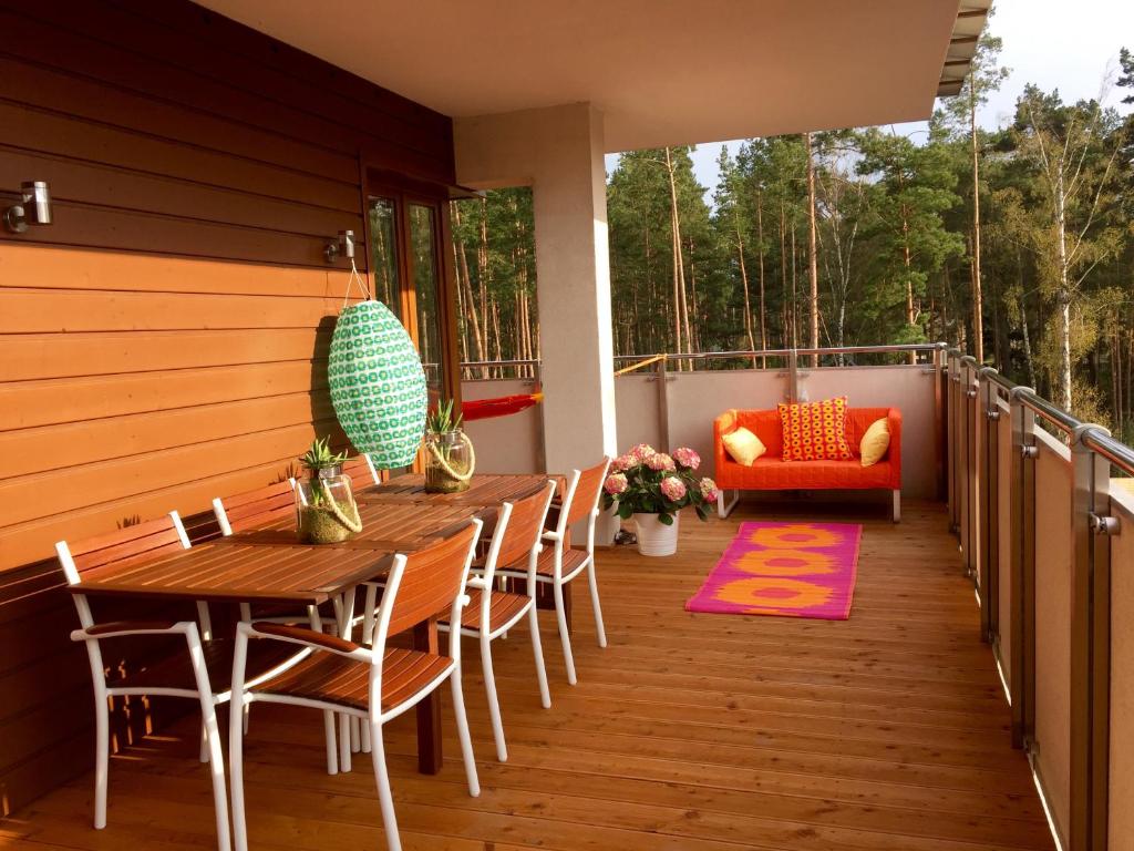 a porch with a wooden table and chairs on a deck at Apartamenty Flaming Baltic Park Stegna in Stegna