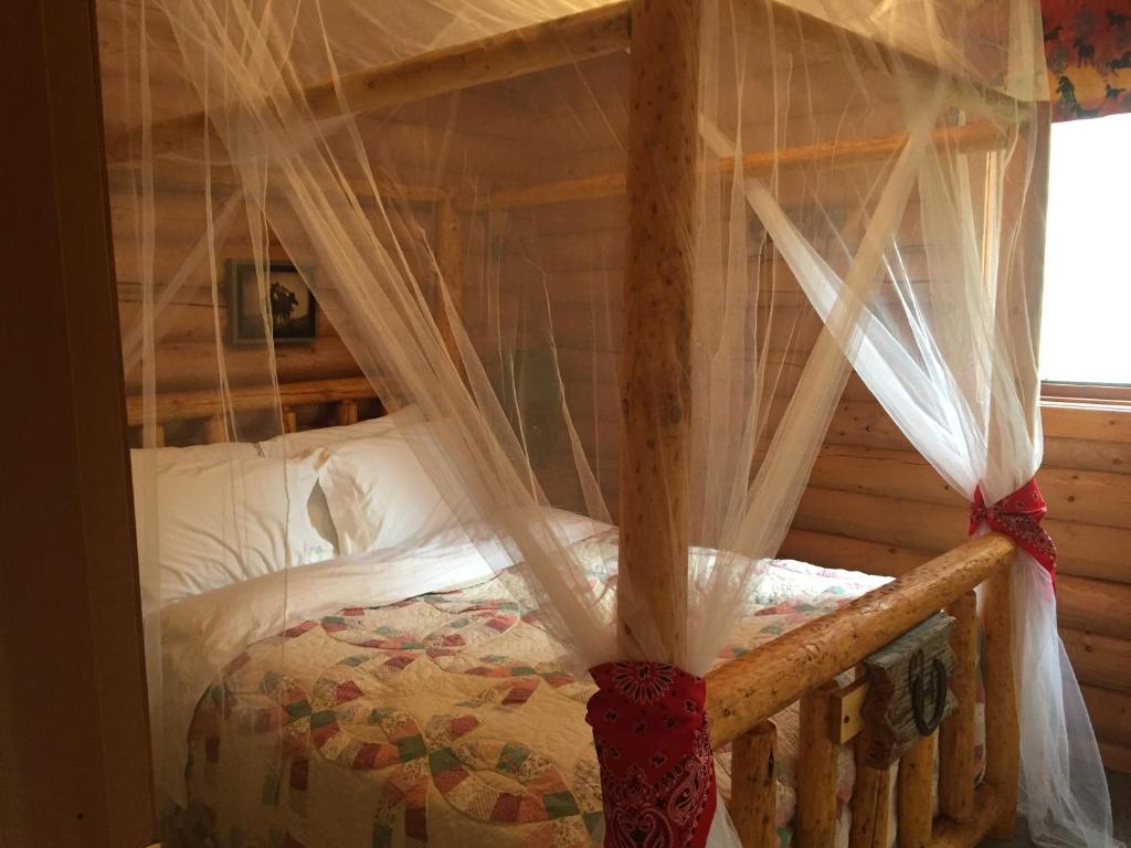 1 dormitorio con cama con dosel y mosquiteras en Montana Hill Guest Ranch en Bridge Lake