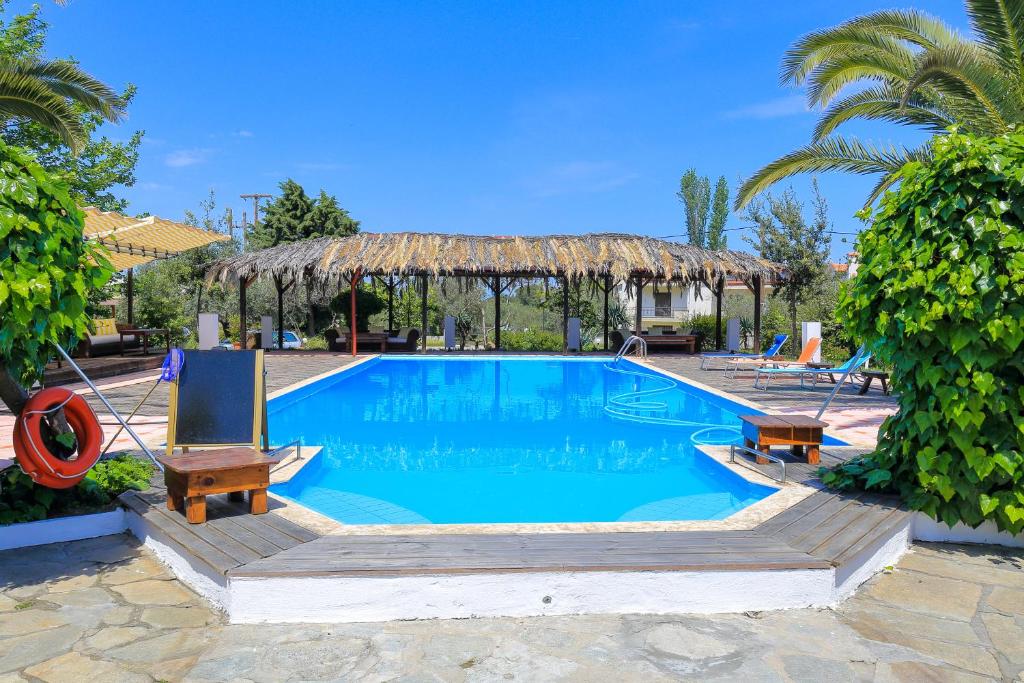 a pool with two chairs and a gazebo at Kissos Apartments in Vourvourou