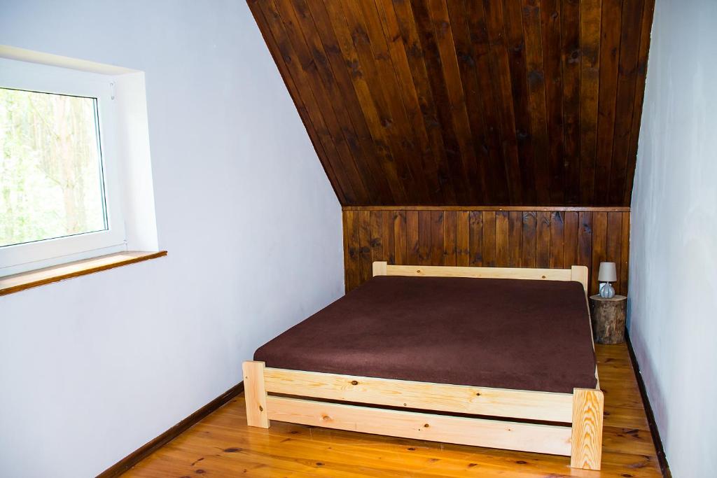 a bed in a room with a wooden ceiling at Kurort Mirowice in Mirowice