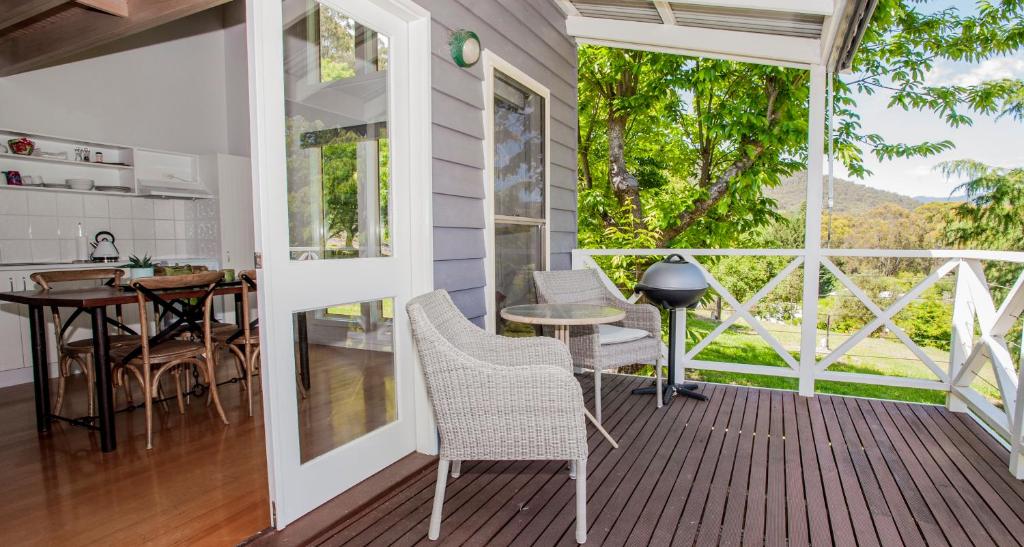 une maison avec une terrasse couverte dotée d'une table et de chaises dans l'établissement Abbys Cottages Bright, à Bright