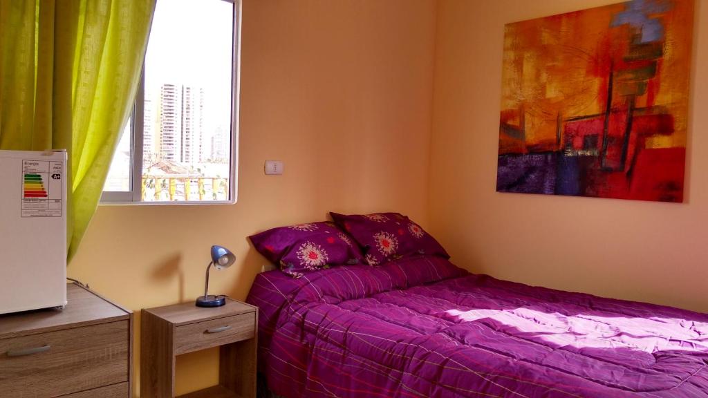 1 dormitorio con cama morada y ventana en Iquique sun, en Iquique
