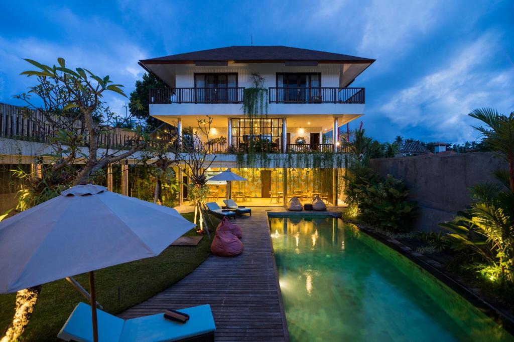 a house with a swimming pool and an umbrella at Athaya Ubud in Ubud