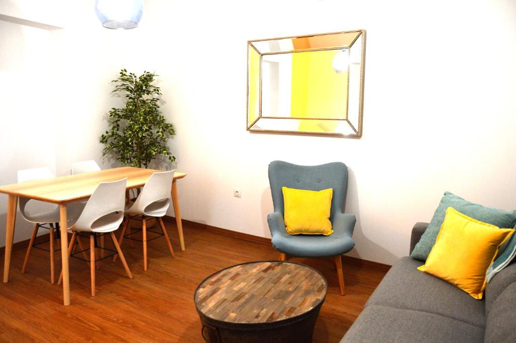 een woonkamer met een tafel, stoelen en een bank bij La Casa del Reloj Cadiz in Cádiz