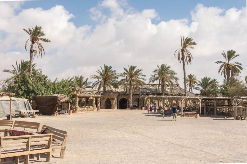a large building with palm trees in the background at Kfar Hanokdim - Glamping & Camping in Arad