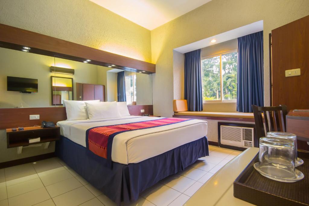 a hotel room with a bed and a desk and a table with a desk at Microtel by Wyndham Eagle Ridge in General Trias