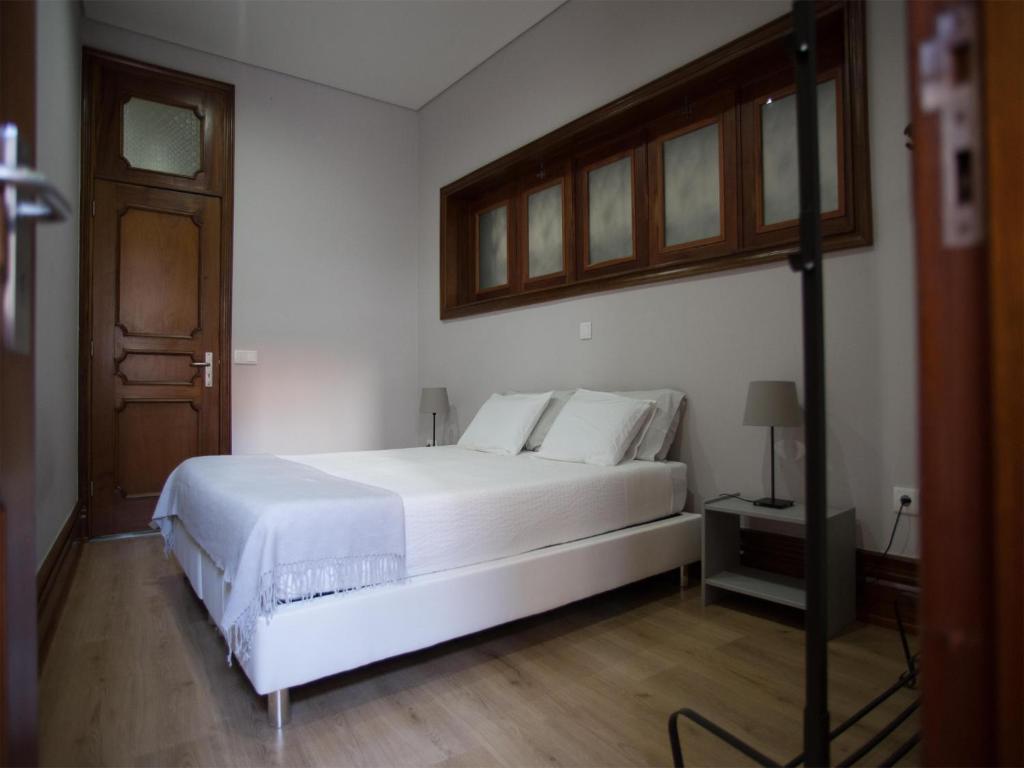 sypialnia z białym łóżkiem i drewnianą podłogą w obiekcie Nidos Accommodation Gaia w mieście Vila Nova de Gaia
